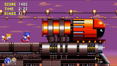 Une screenshot d'un jeu Sonic en style 16 bit/pixel art, ou Sonic et Tails courrent sur un train et se rapprochent de la locomotive, sur un fond de lever ou couché de soleil.
